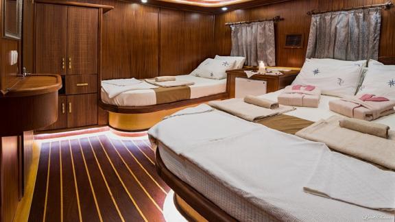 Full view of the triple cabin with one single bed and one beautifully decorated double bed.